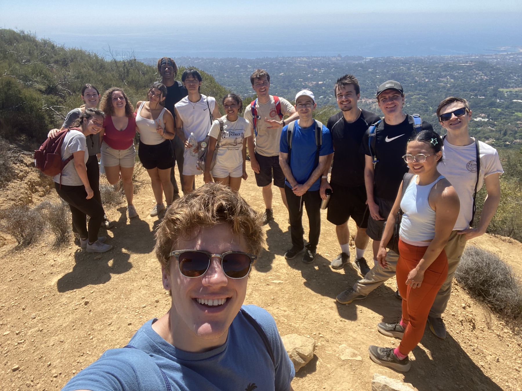 Self-Improvement Club members smiling together on a sunny coastal hike