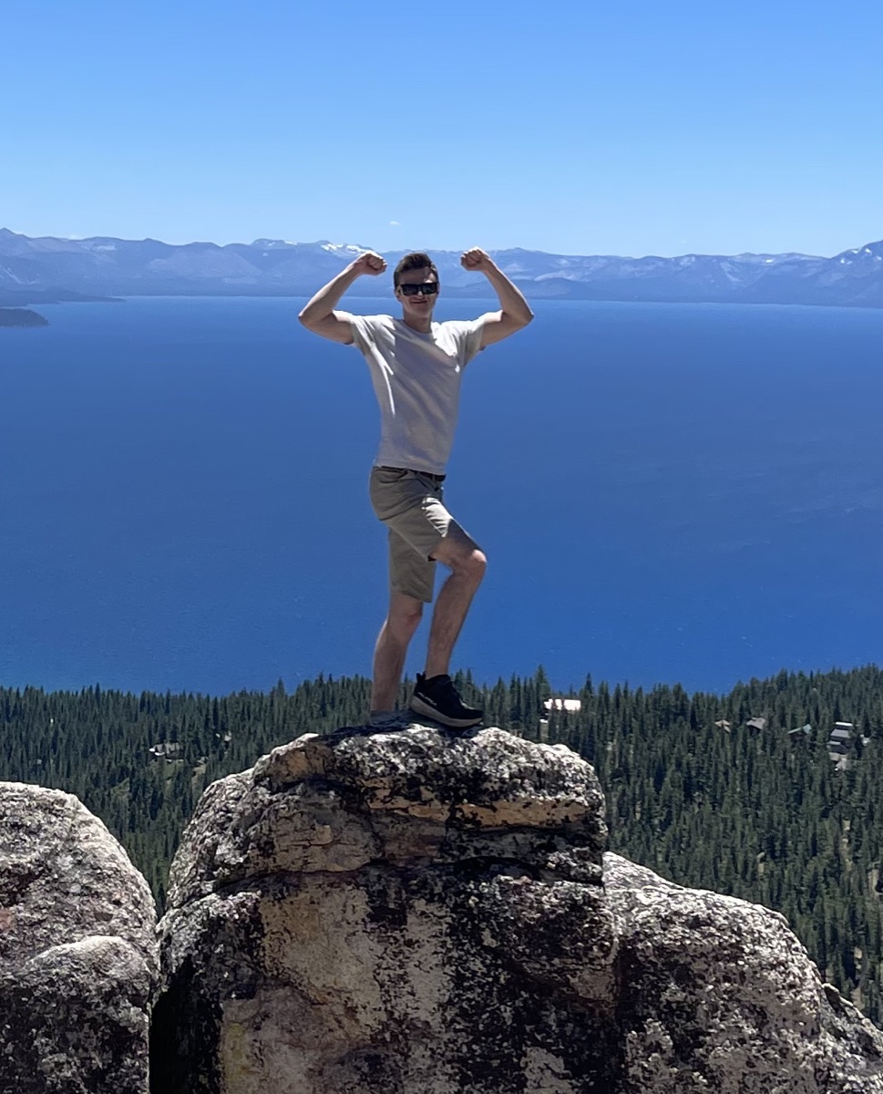 Drew McDonald standing on a rock above a mountain lake