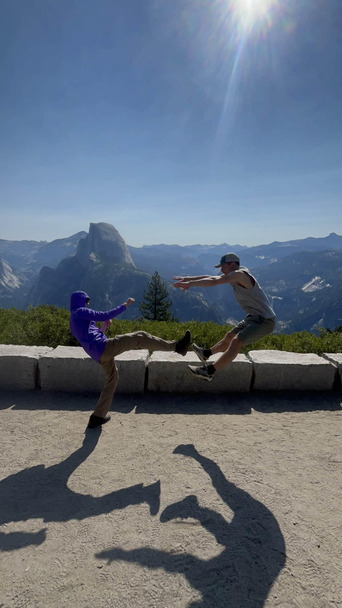 Two club members jumping playfully with Half Dome behind them